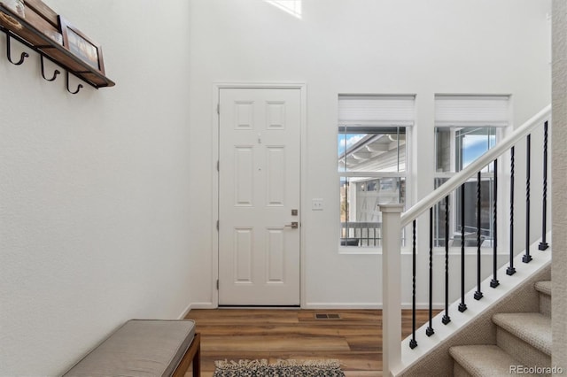 foyer entrance with stairway, baseboards, and wood finished floors