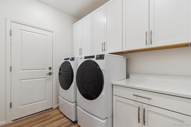 clothes washing area with light wood-type flooring, cabinet space, and separate washer and dryer