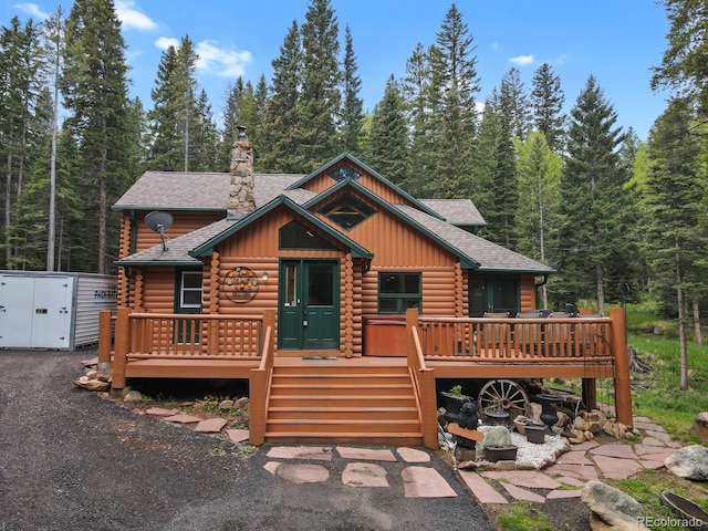 8905 Carol Ln, Conifer, CO 80433 - view of front of property featuring log siding, a shingled roof, board and batten siding, and a chimney