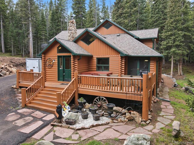 8905 Carol Ln, Conifer, CO 80433 - view of front of house featuring log exterior, a shingled roof, board and batten siding, a chimney, and a wooden deck