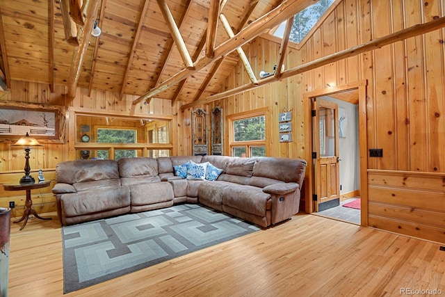 8905 Carol Ln, Conifer, CO 80433 - living area featuring wood walls, light wood-style floors, a skylight, wood ceiling with exposed beams, and high vaulted ceiling
