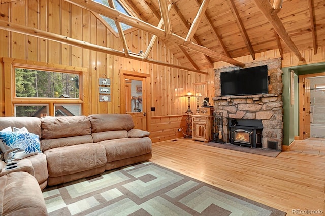 8905 Carol Ln, Conifer, CO 80433 - living area featuring high vaulted ceiling, wood finished floors, wooden walls, a wood stove, and wood ceiling with exposed beams