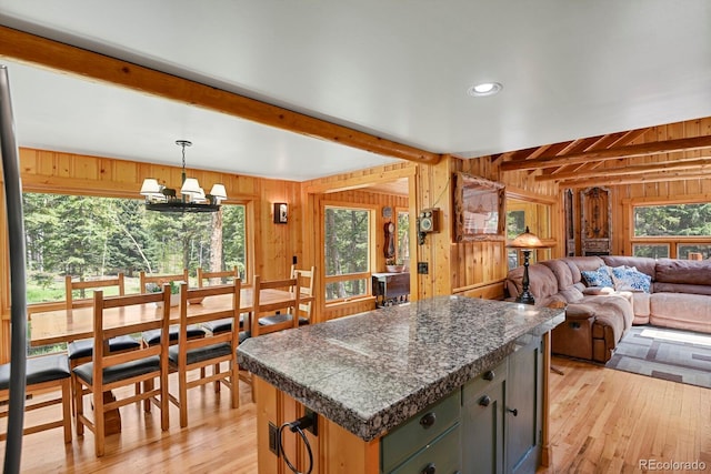 8905 Carol Ln, Conifer, CO 80433 - kitchen with wood walls, beam ceiling, light wood finished floors, a chandelier, and a kitchen island