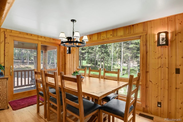 8905 Carol Ln, Conifer, CO 80433 - dining area featuring a chandelier, wooden walls, light wood-style floors, and healthy amount of natural light