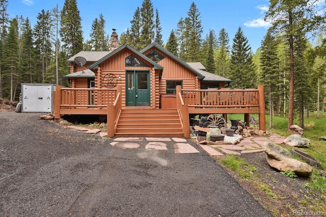 8905 Carol Ln, Conifer, CO 80433 - log cabin with log siding, a chimney, a wooden deck, board and batten siding, and a shingled roof