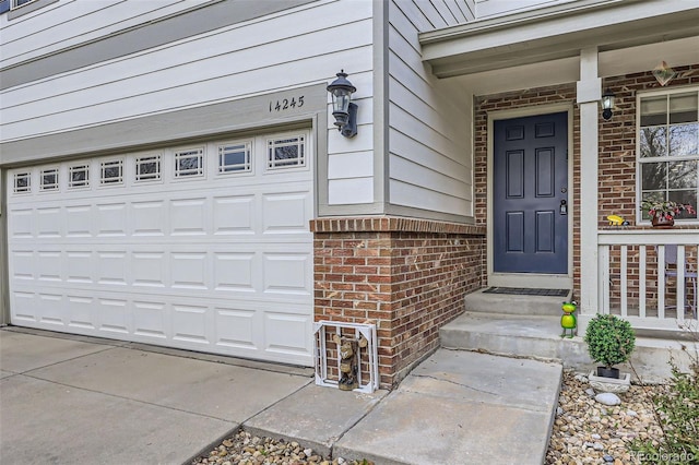 view of exterior entry featuring a garage, a porch, and brick siding