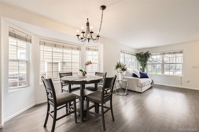 dining space featuring baseboards, wood finished floors, a notable chandelier, and a healthy amount of sunlight