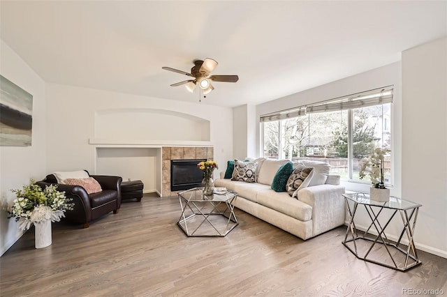 living room featuring baseboards, ceiling fan, wood finished floors, and a fireplace