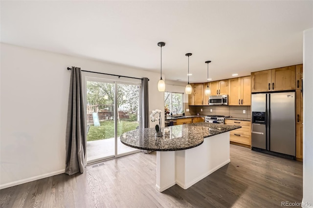 kitchen featuring a kitchen island, stainless steel appliances, dark stone countertops, and wood finished floors