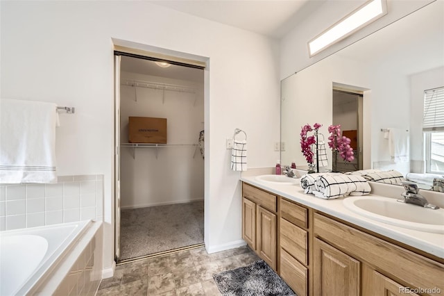 full bathroom featuring a sink, a walk in closet, a garden tub, and double vanity