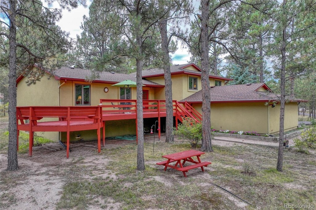 8510 Wilderness Dr, Colorado Springs, CO 80908 - back of house with roof with shingles, stucco siding, stairs, and a wooden deck