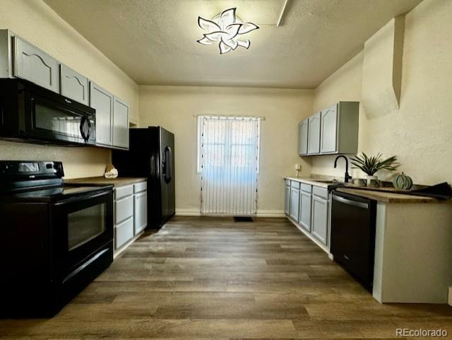 kitchen featuring black appliances, dark hardwood / wood-style floors, sink, and a textured ceiling