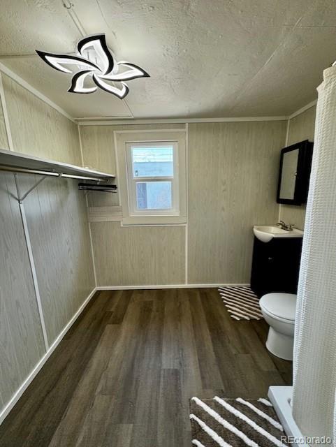 bathroom with wood walls, a chandelier, toilet, vanity, and hardwood / wood-style flooring