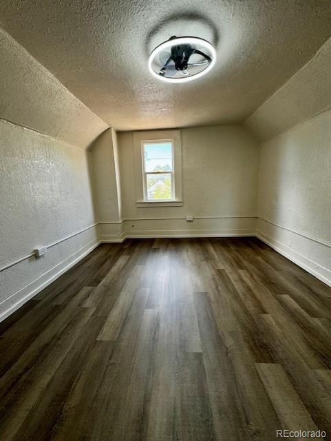 bonus room with dark hardwood / wood-style flooring, a textured ceiling, and vaulted ceiling