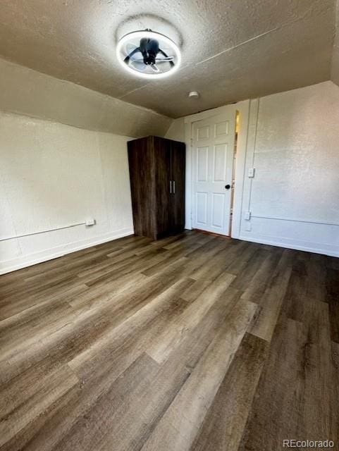 additional living space featuring lofted ceiling, wood-type flooring, and a textured ceiling