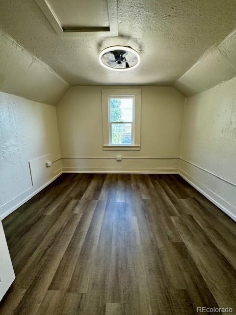 additional living space with a textured ceiling, dark hardwood / wood-style floors, and lofted ceiling