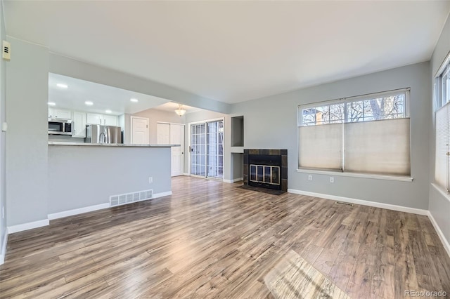 unfurnished living room with a tile fireplace and light hardwood / wood-style flooring