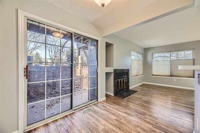 interior space with a tiled fireplace and wood-type flooring