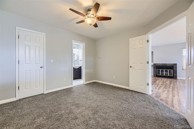 unfurnished bedroom with ensuite bathroom, carpet floors, ceiling fan, and a fireplace