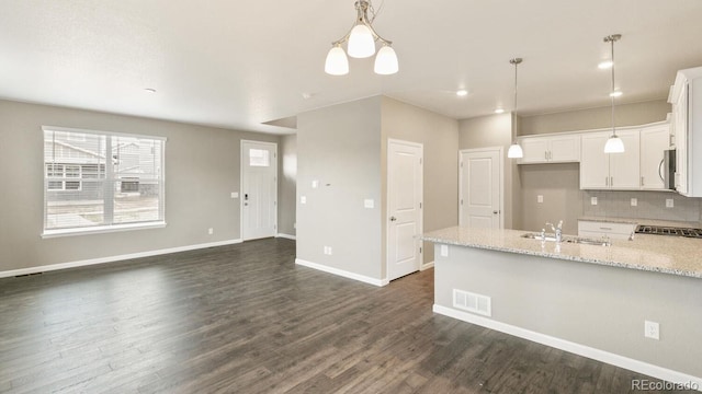 kitchen featuring white cabinetry, tasteful backsplash, sink, hanging light fixtures, and light stone counters