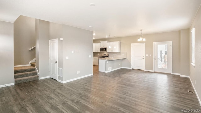 unfurnished living room with dark wood-type flooring, a wealth of natural light, and an inviting chandelier