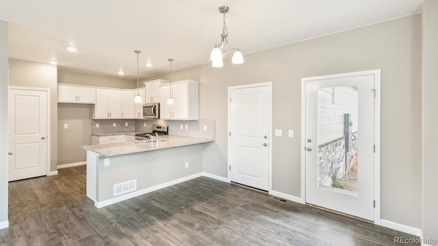 kitchen with backsplash, kitchen peninsula, hanging light fixtures, appliances with stainless steel finishes, and white cabinets