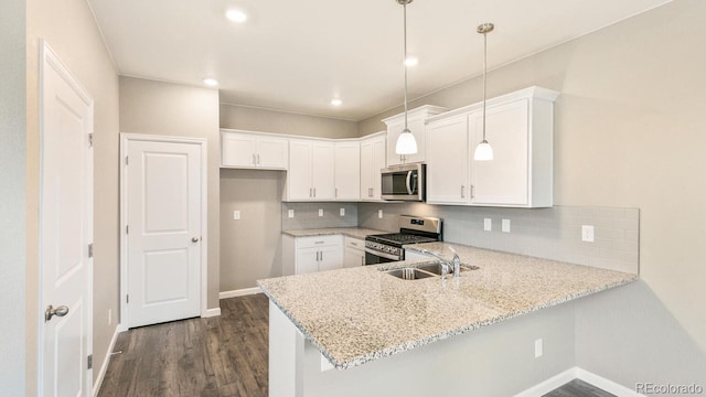 kitchen featuring decorative light fixtures, white cabinetry, stainless steel appliances, sink, and kitchen peninsula