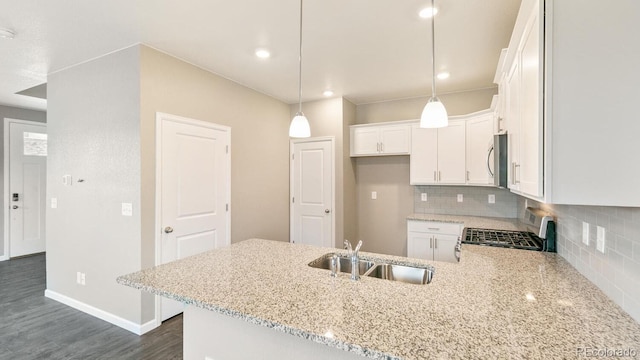 kitchen featuring stove, decorative backsplash, sink, light stone countertops, and white cabinets