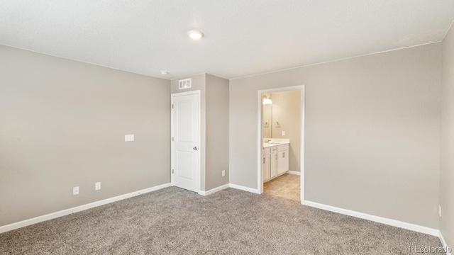 unfurnished bedroom featuring ensuite bathroom and light colored carpet