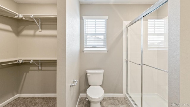 bathroom featuring toilet and a shower with shower door