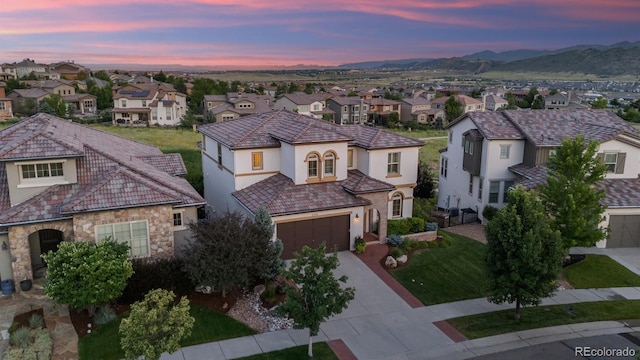 2234 S Nile St, Denver, CO 80228 - mediterranean / spanish-style home featuring a residential view, stucco siding, stone siding, driveway, and a mountain view