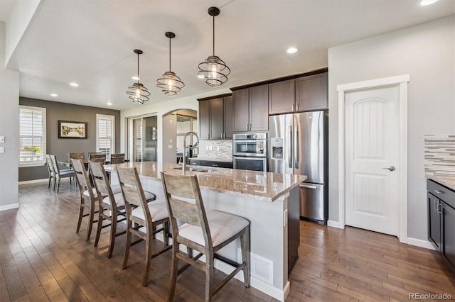 2234 S Nile St, Denver, CO 80228 - kitchen with stainless steel appliances, arched walkways, decorative backsplash, dark wood-style flooring, and light stone countertops