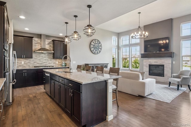 2234 S Nile St, Denver, CO 80228 - kitchen featuring wall chimney exhaust hood, a breakfast bar, dark wood-style flooring, plenty of natural light, and recessed lighting