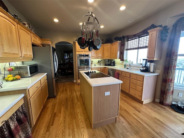 10520 W Vassar Dr, Lakewood, CO 80227 - kitchen featuring arched walkways, appliances with stainless steel finishes, light wood-type flooring, a center island, and light countertops