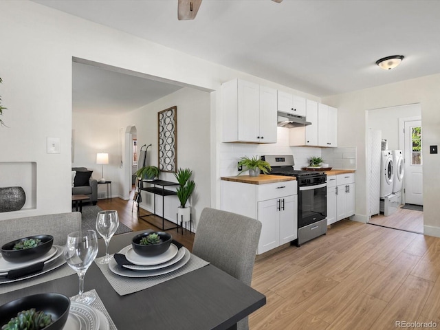 4740 W Wyoming Pl, Denver, CO 80219 - kitchen with stainless steel gas stove, washing machine and clothes dryer, butcher block counters, under cabinet range hood, and white cabinetry