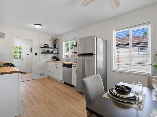 4740 W Wyoming Pl, Denver, CO 80219 - kitchen with butcher block counters, stainless steel appliances, open shelves, light wood-style flooring, and a sink