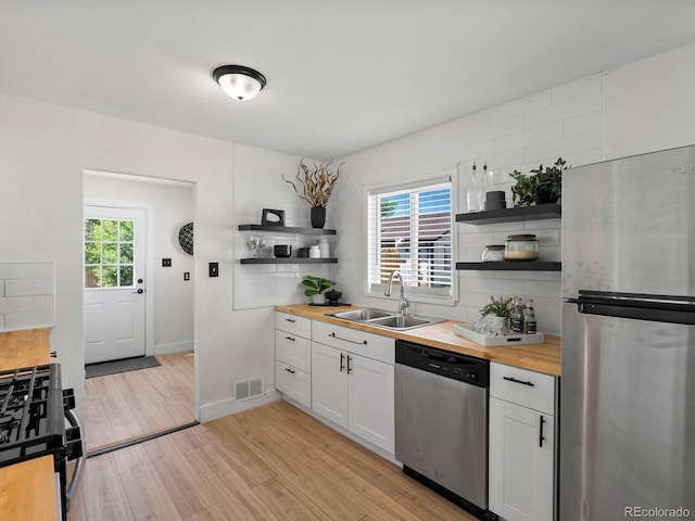4740 W Wyoming Pl, Denver, CO 80219 - kitchen with butcher block counters, appliances with stainless steel finishes, open shelves, and a sink