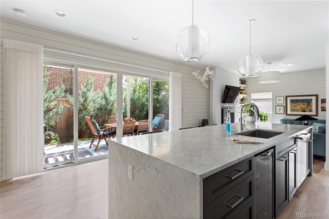 501 S Race St, Denver, CO 80209 - kitchen with a sink, light wood-type flooring, light stone countertops, a kitchen island with sink, and pendant lighting
