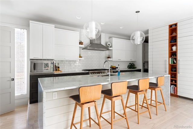 501 S Race St, Denver, CO 80209 - kitchen featuring stainless steel microwave, wall chimney exhaust hood, backsplash, a sink, and light wood-style floors