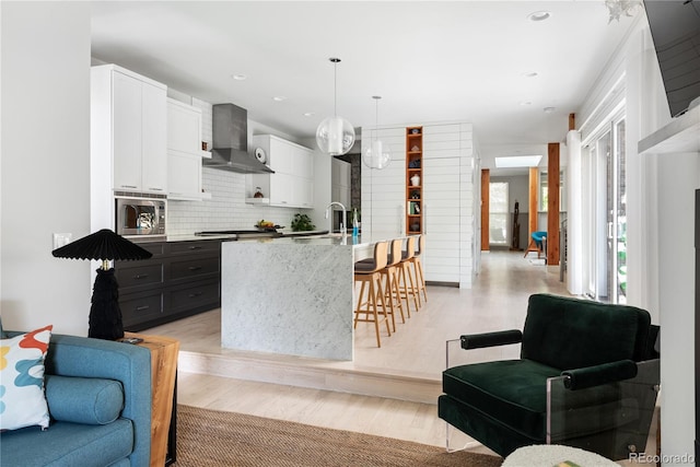 501 S Race St, Denver, CO 80209 - kitchen featuring wall chimney range hood, appliances with stainless steel finishes, a kitchen bar, open floor plan, and recessed lighting