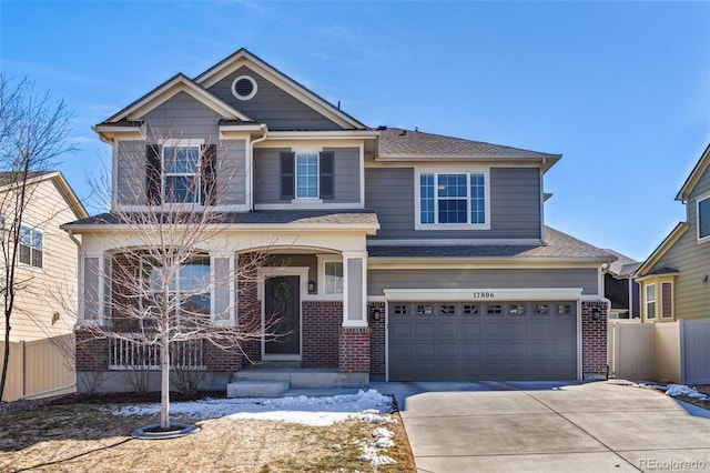 craftsman inspired home featuring concrete driveway, an attached garage, fence, and brick siding