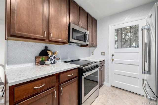 7912 Fenton St, Arvada, CO 80003 - kitchen featuring appliances with stainless steel finishes, light stone countertops, light tile patterned floors, and backsplash