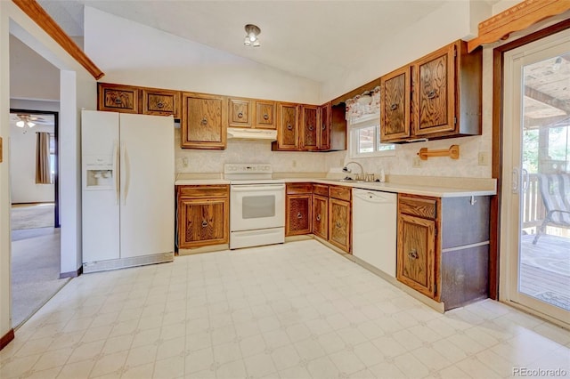4738 Dover Dr, Colorado Springs, CO 80916 - kitchen with white appliances, under cabinet range hood, vaulted ceiling, light flooring, and brown cabinetry