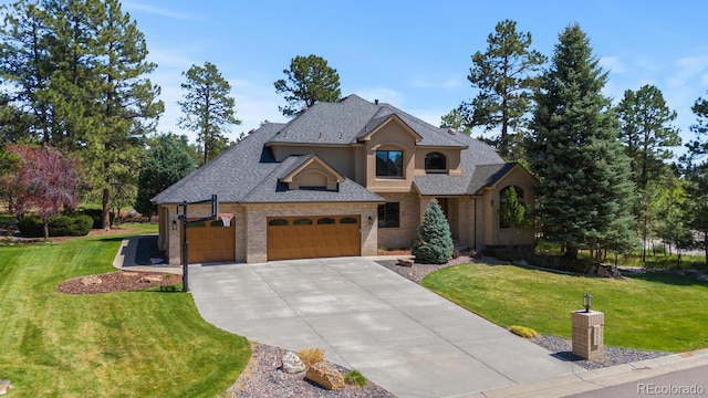view of front of home featuring an attached garage, brick siding, driveway, and a front lawn