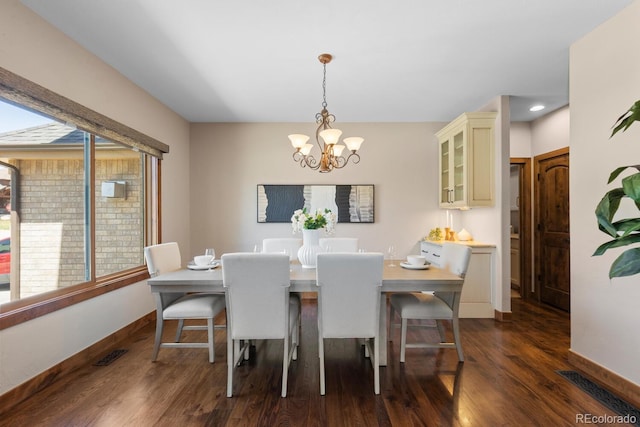 dining room with dark wood finished floors, a chandelier, baseboards, and visible vents