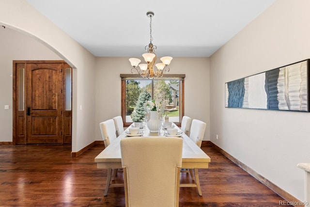 dining space with an inviting chandelier, arched walkways, baseboards, and wood finished floors