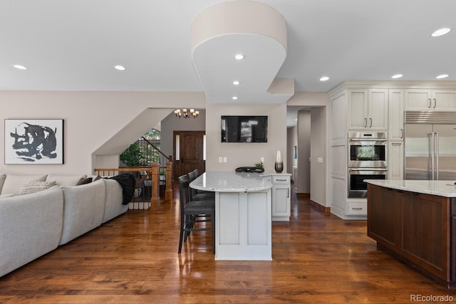 kitchen featuring stainless steel appliances, light stone counters, a kitchen bar, and open floor plan