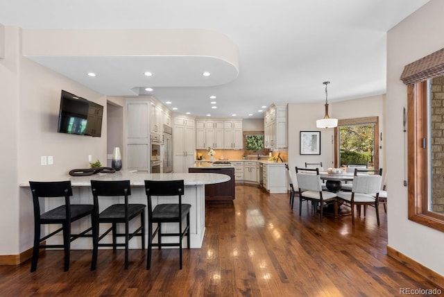 kitchen with a peninsula, a breakfast bar area, dark wood-type flooring, and light stone countertops