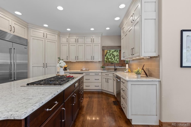 kitchen with light stone countertops, tasteful backsplash, appliances with stainless steel finishes, and dark brown cabinetry