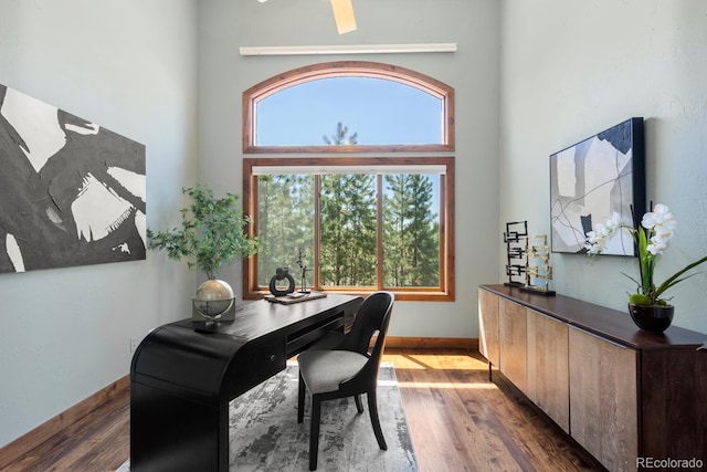 office with a high ceiling, baseboards, and wood finished floors